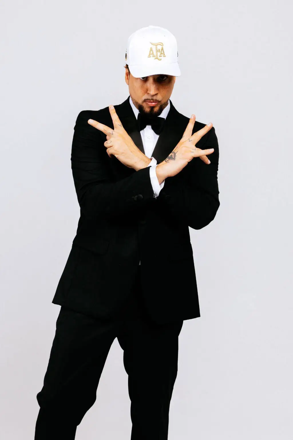 Dante con traje negro y gorra blanca